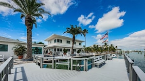 A waterfront property with a dock, palm trees, and a flag.
