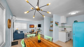 A compact living space with a dining area, kitchenette, and a seating area with a sofa and chairs.