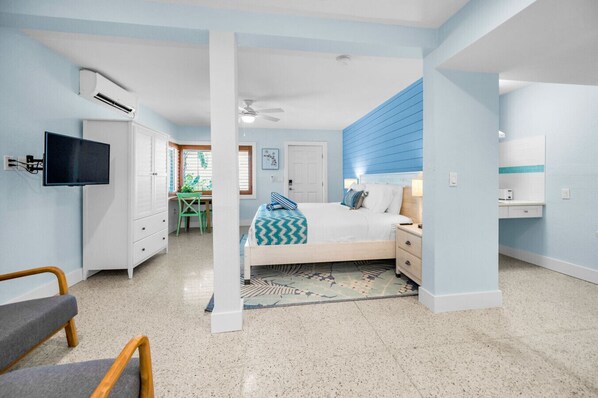 Un dormitorio con cama, mesita de noche y escritorio con silla.