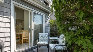 A covered patio with a sliding glass door leading to a kitchen area, wicker chairs, and a small table.