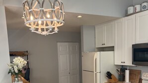 A modern kitchen with a wooden island, white cabinets, a stainless steel refrigerator, and a built-in oven.