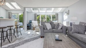 A modern living room with a grey sofa, a coffee table, and a bar area with stools.