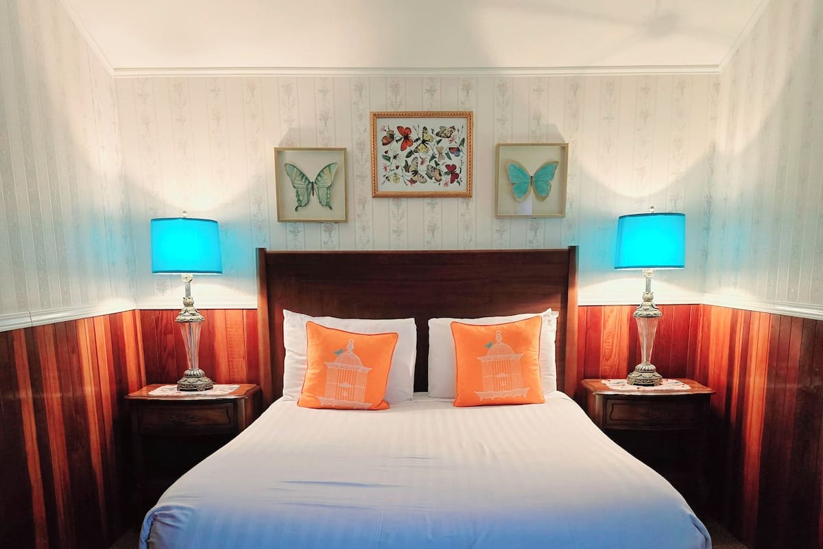 A hotel room with a large bed, two nightstands, and two wall-mounted lamps.