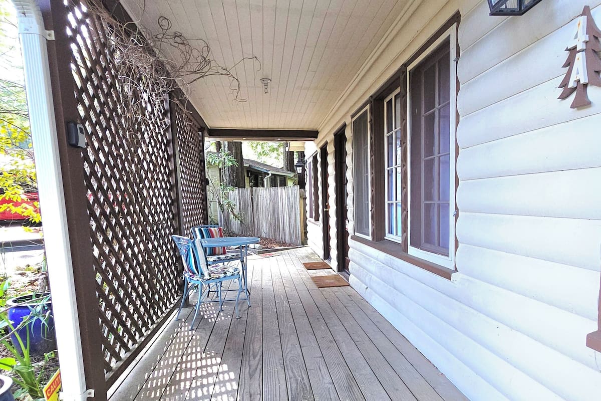 A wooden porch with a patterned rug, a metal chair, and a wooden fence.