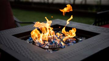 A square metal fire pit with flames.