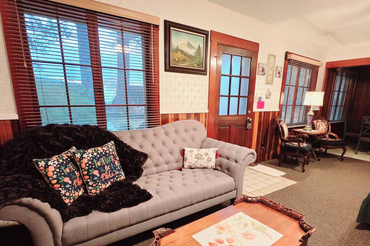 A living room with a grey sofa, a wooden coffee table, and a patterned throw blanket.