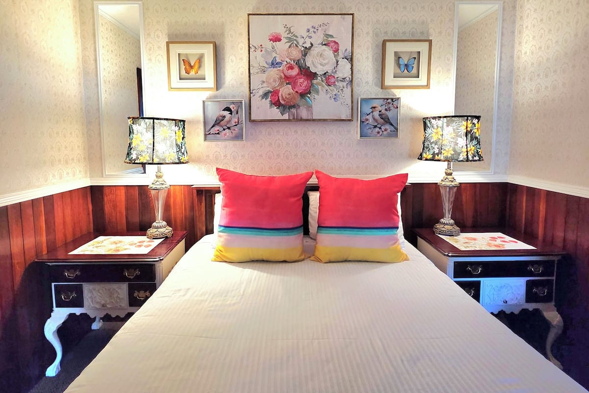 A hotel room with a large bed, two nightstands, a mirror, and wall-mounted artwork.