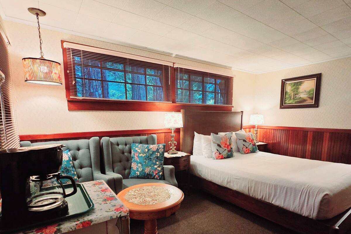 A hotel room with a bed, a sofa, a coffee maker, and a small table with a tray.