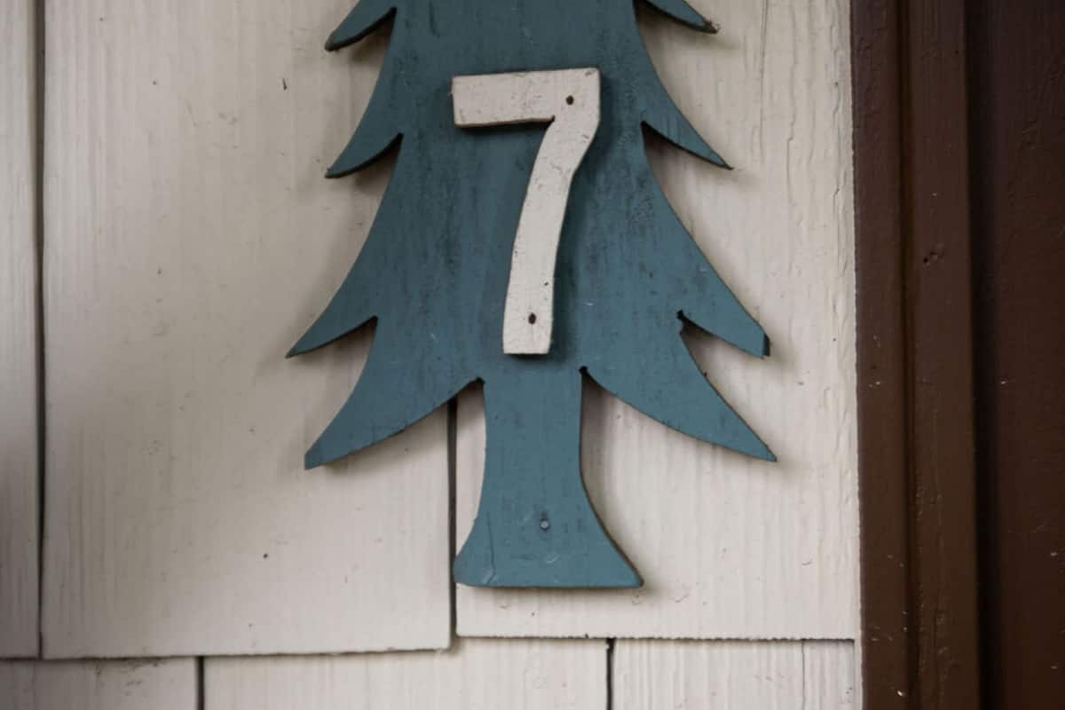 A wooden house number sign shaped like a tree with the number 7.