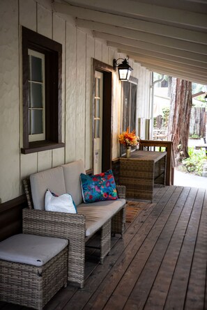 Eine überdachte Veranda mit Korbmöbeln, einem Tisch mit Blumenvase und einem Holzbalkon.
