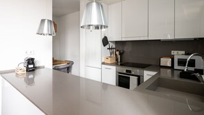 A modern kitchen with white cabinets, stainless steel appliances, and a large island. - Apartment with spectacular terrace in the center of Barcelona (Barcelona)