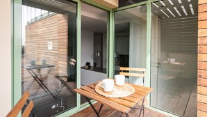A glass-enclosed balcony with a wooden table and chairs, two white mugs on the table, and a view of the outside through the glass. - Apartment with spectacular terrace in the center of Barcelona (Barcelona)