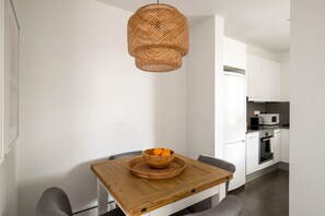 Une cuisine moderne avec des meubles blancs, un four à micro-ondes et un four encastré.