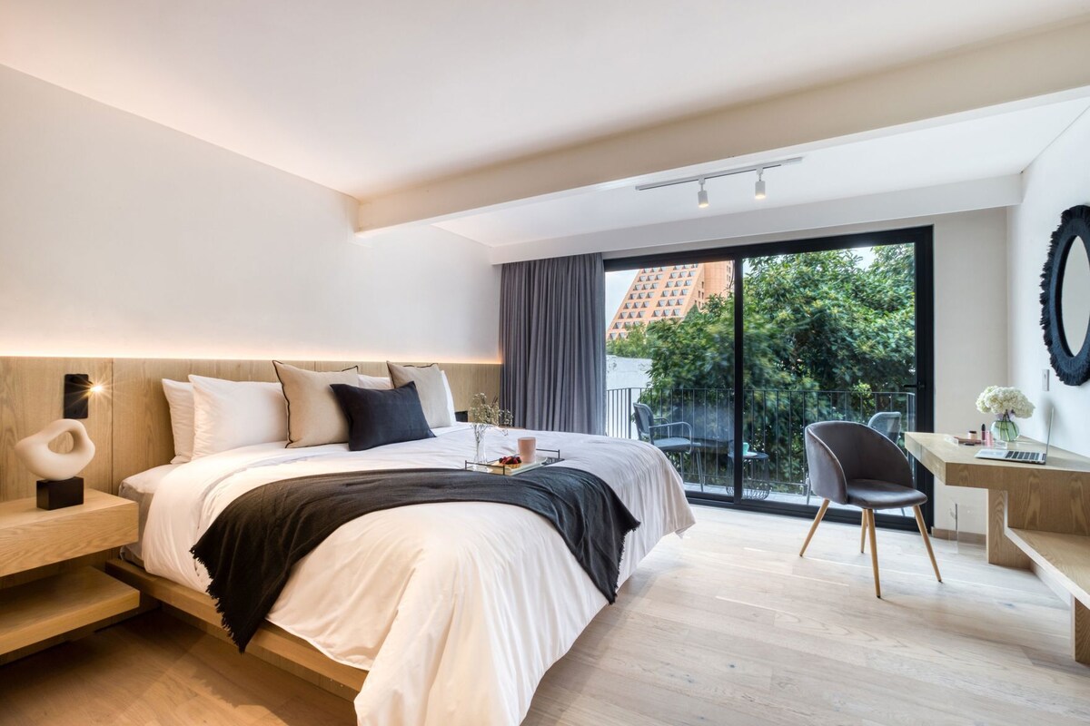 Een moderne hotelkamer met een groot bed, een bureau en uitzicht op de omgeving.