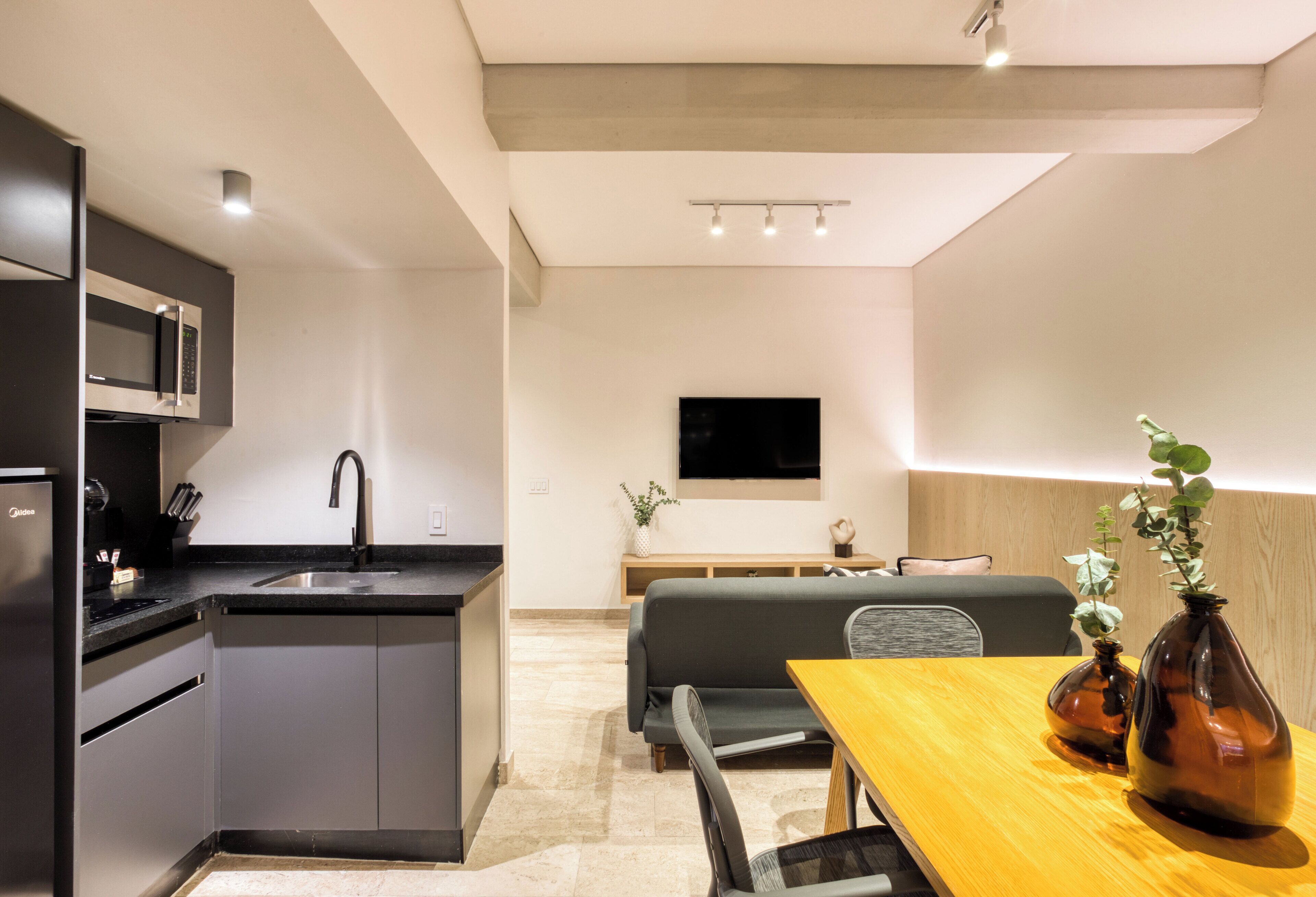 Eine moderne Küche mit integriertem Mikrowellenherd, einer Spüle und einem Essbereich mit Holztisch und Stühlen.