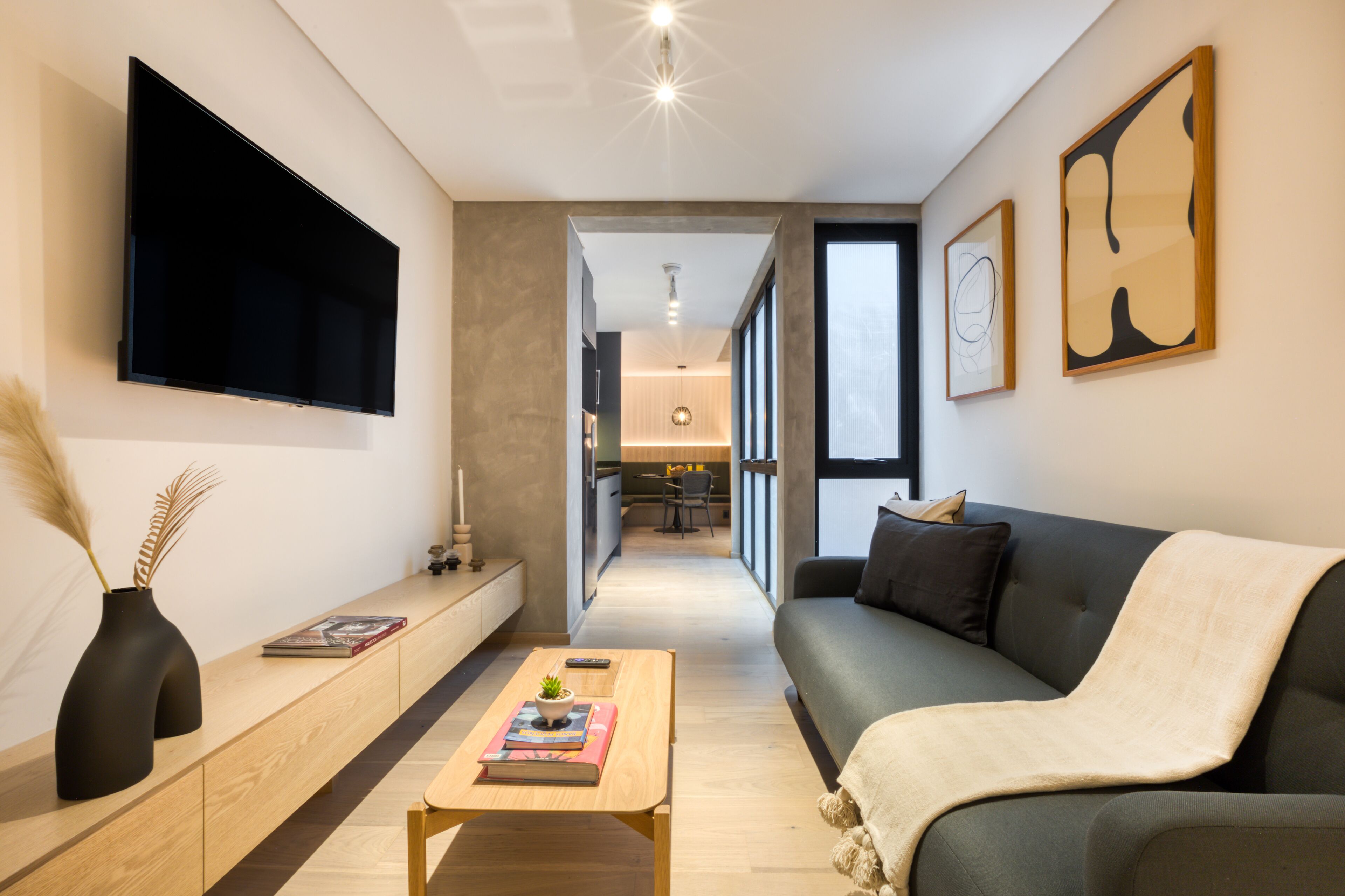 Un salon moderne avec un téléviseur à écran plat, un canapé, une table basse et des œuvres d’art accrochées aux murs.