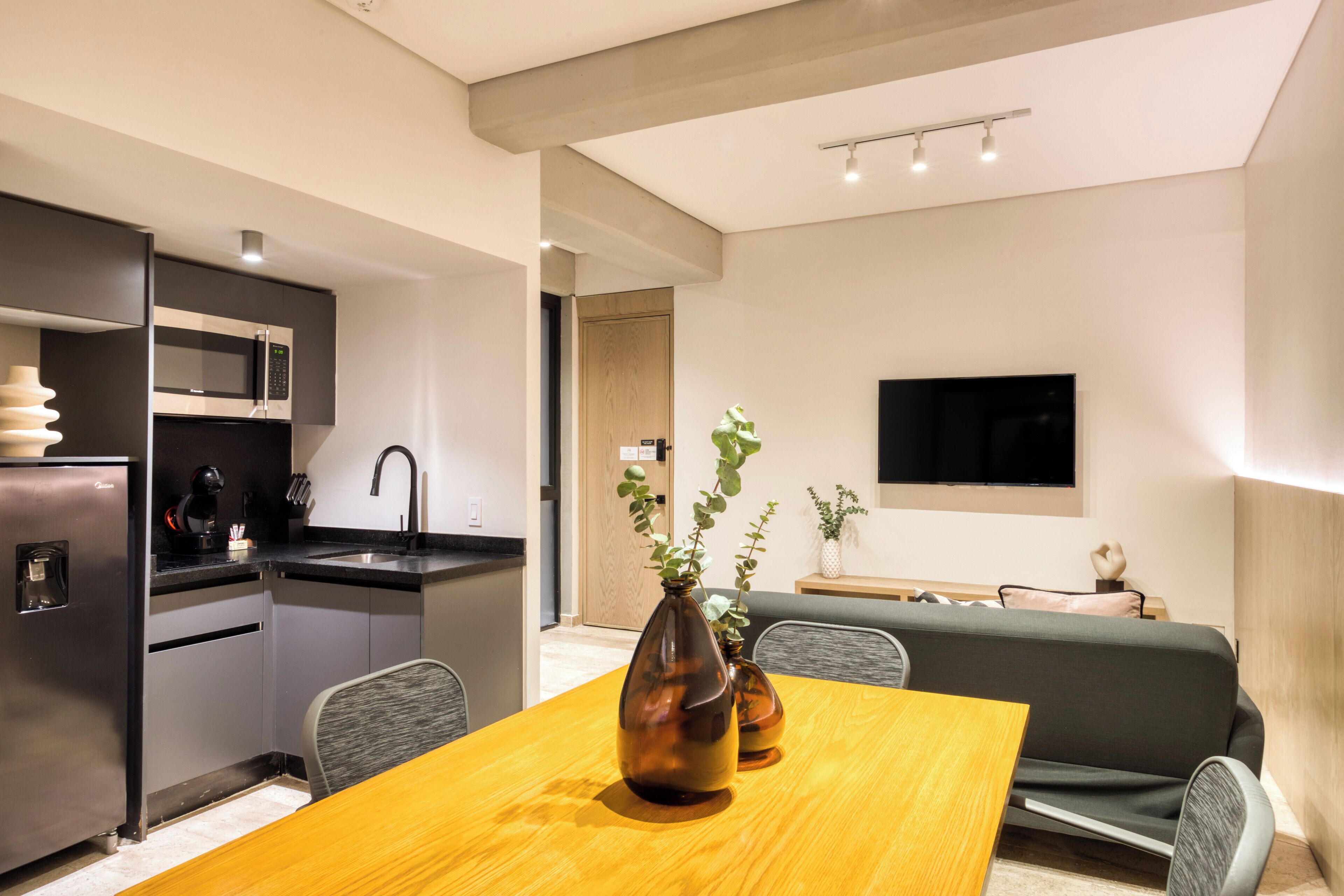 A modern kitchen with a built-in microwave, a sink, and a dining area with a wooden table and chairs.