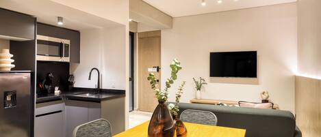 A modern kitchen with a built-in microwave, a sink, and a dining area with a wooden table and chairs.