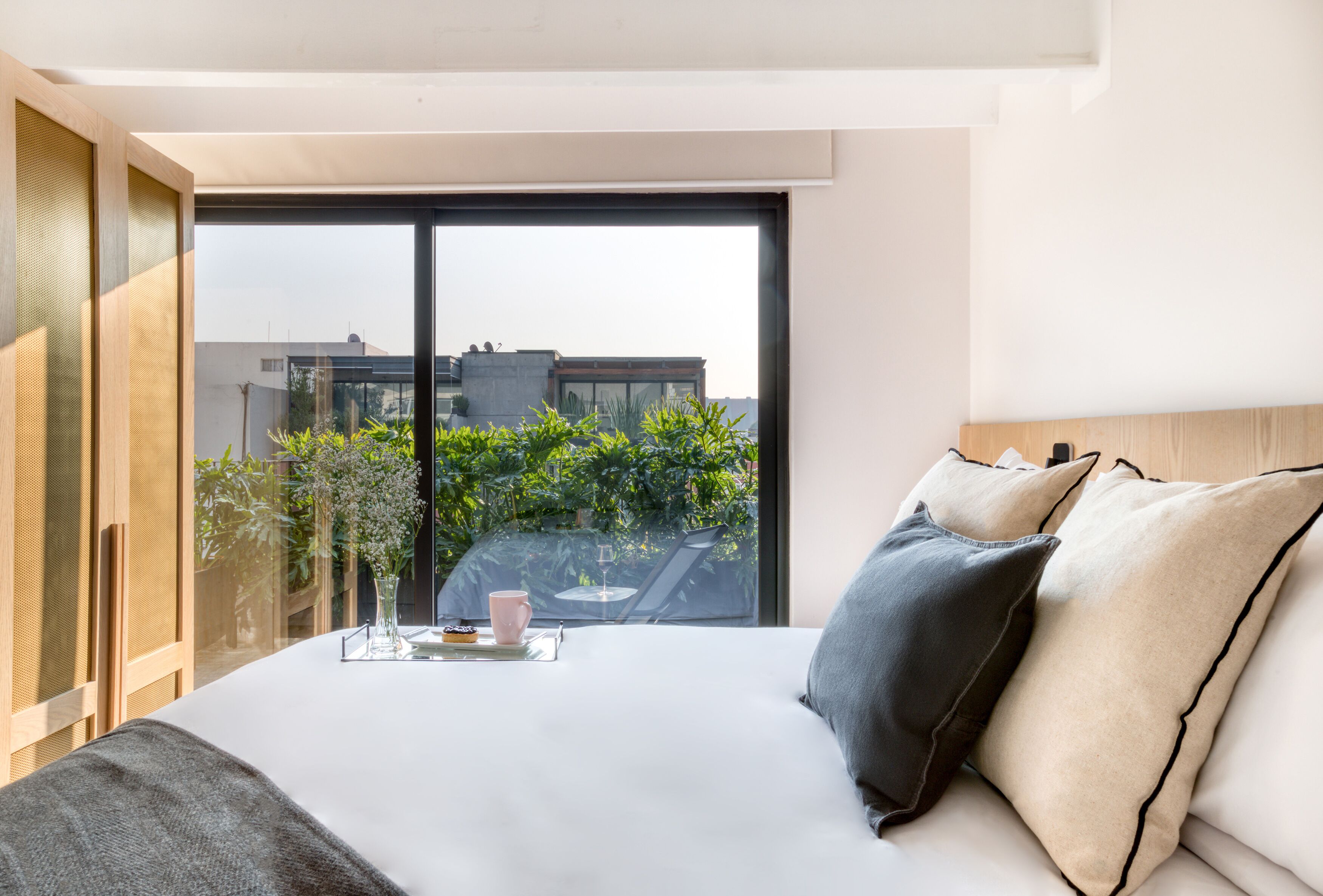 Una habitación de hotel moderna con una cama grande, una pared de vidrio y vistas a la ciudad.