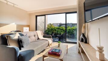 A modern living room with a sofa, coffee table, and a flat-screen TV.