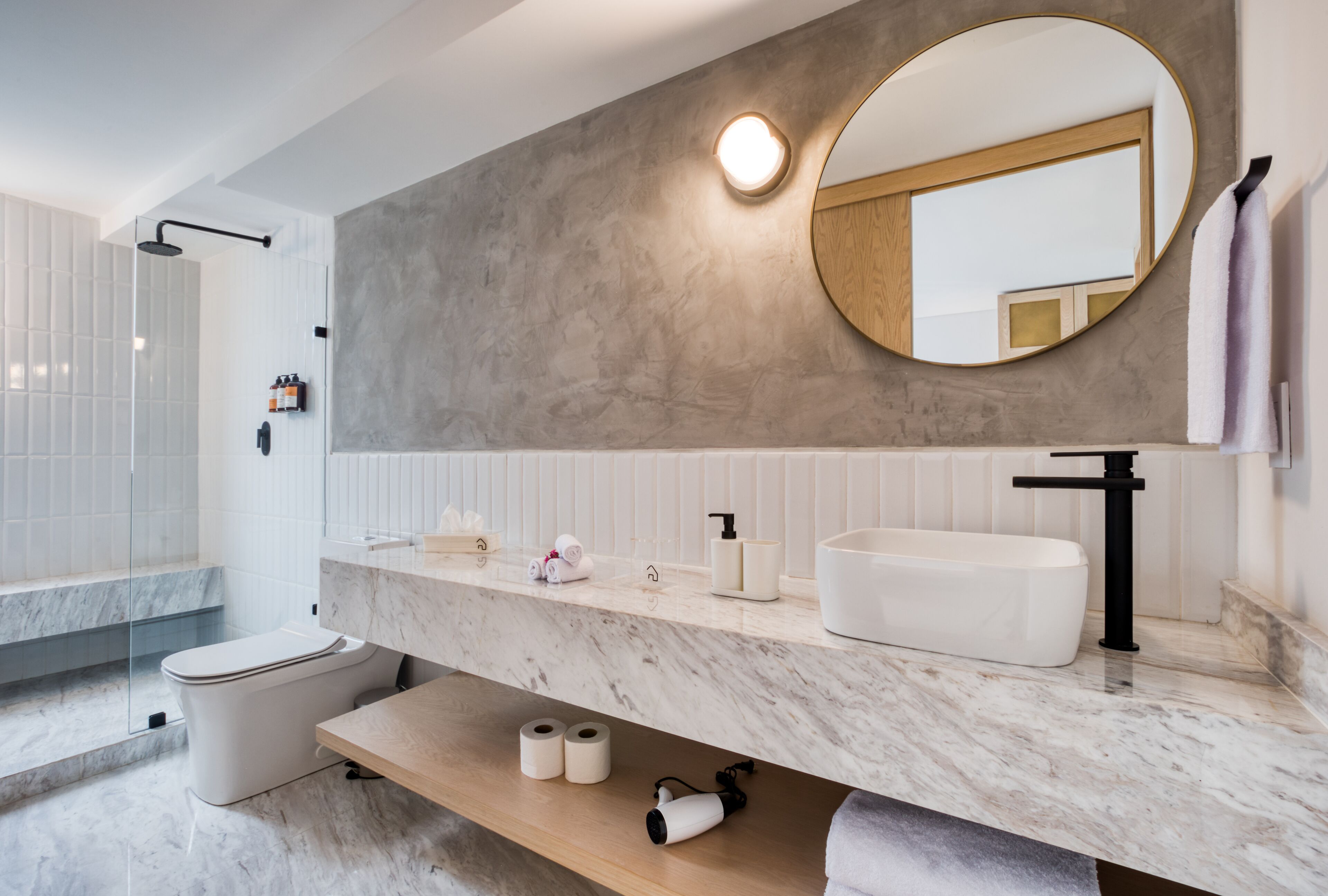 A modern bathroom with a large mirror, white sink, and marble countertop.
