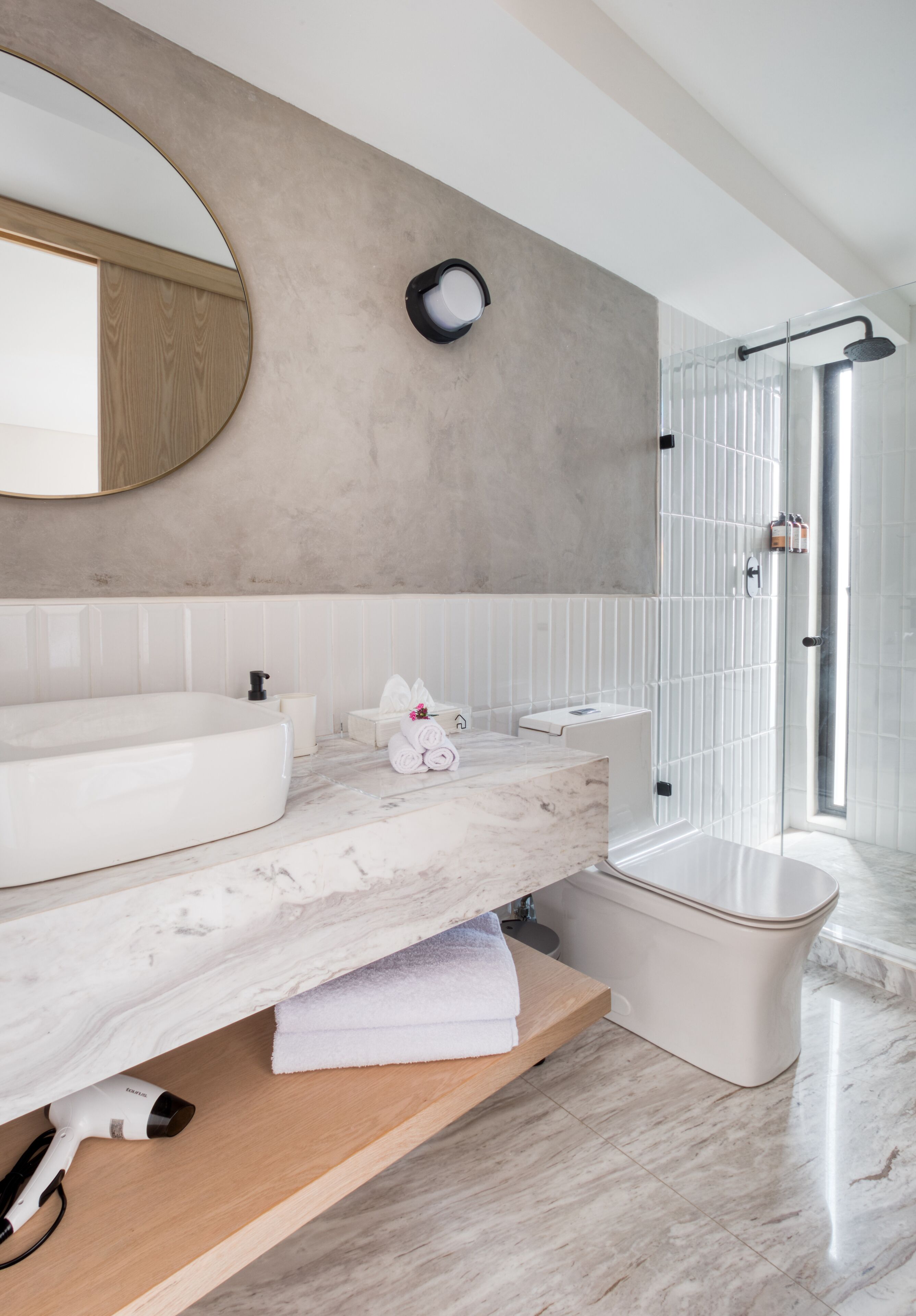 A modern bathroom with a large mirror, a marble countertop, a built-in sink, and a glass-enclosed shower.