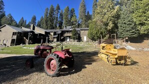 A farmstead with a barn, a red tractor, and a yellow loader.