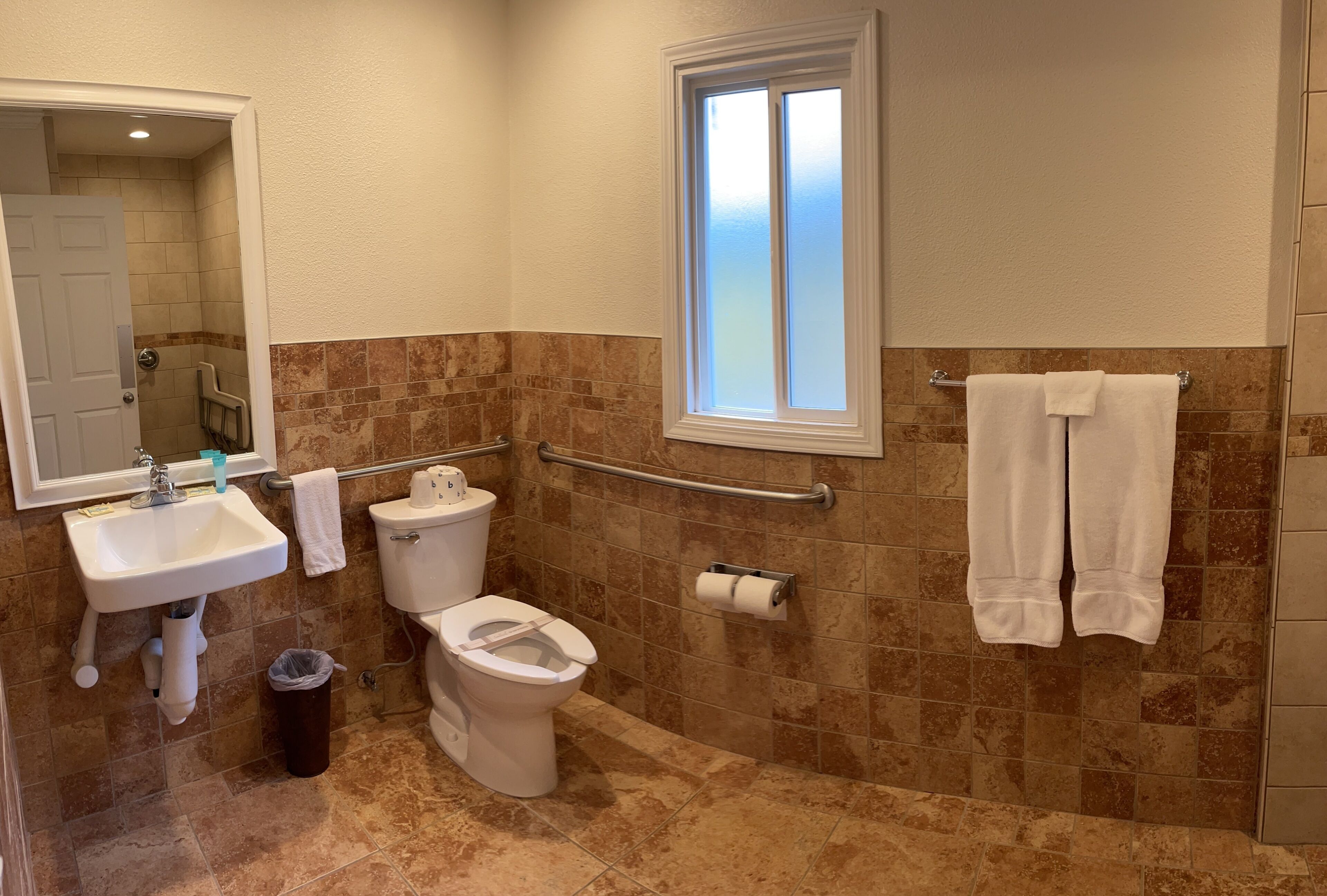 A bathroom with a sink, toilet, and window.