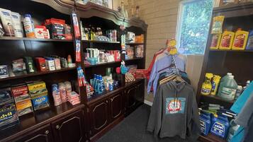 A store with shelves stocked with cleaning supplies, personal care items, and a rack of clothing.