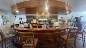 A coffee shop with a wooden counter, bar stools, and a chalkboard menu.