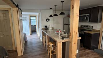 Une cuisine moderne avec des éléments en bois, un îlot central doté de tabourets et une vue sur la salle à manger.