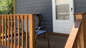 A wooden deck with a railing, a door, and a chair.