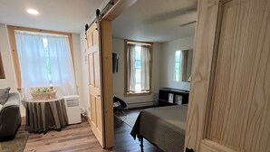 A room with a bed, a desk, a chair, and a window with curtains.