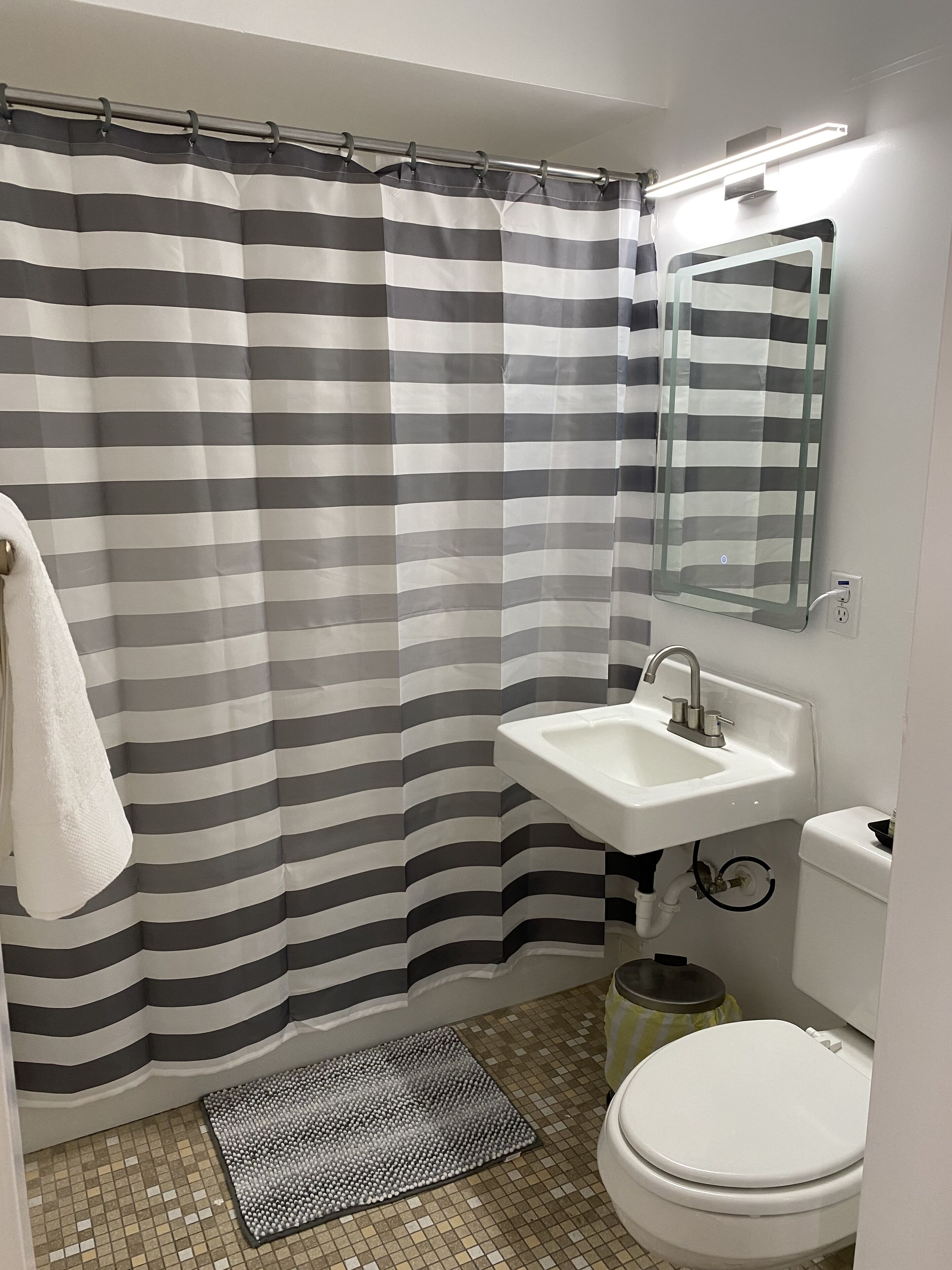 Bañera con ducha, toallas, jabón, shampoo