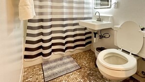 Une salle de bain avec un rideau de douche à rayures, un lavabo, des toilettes et un miroir.