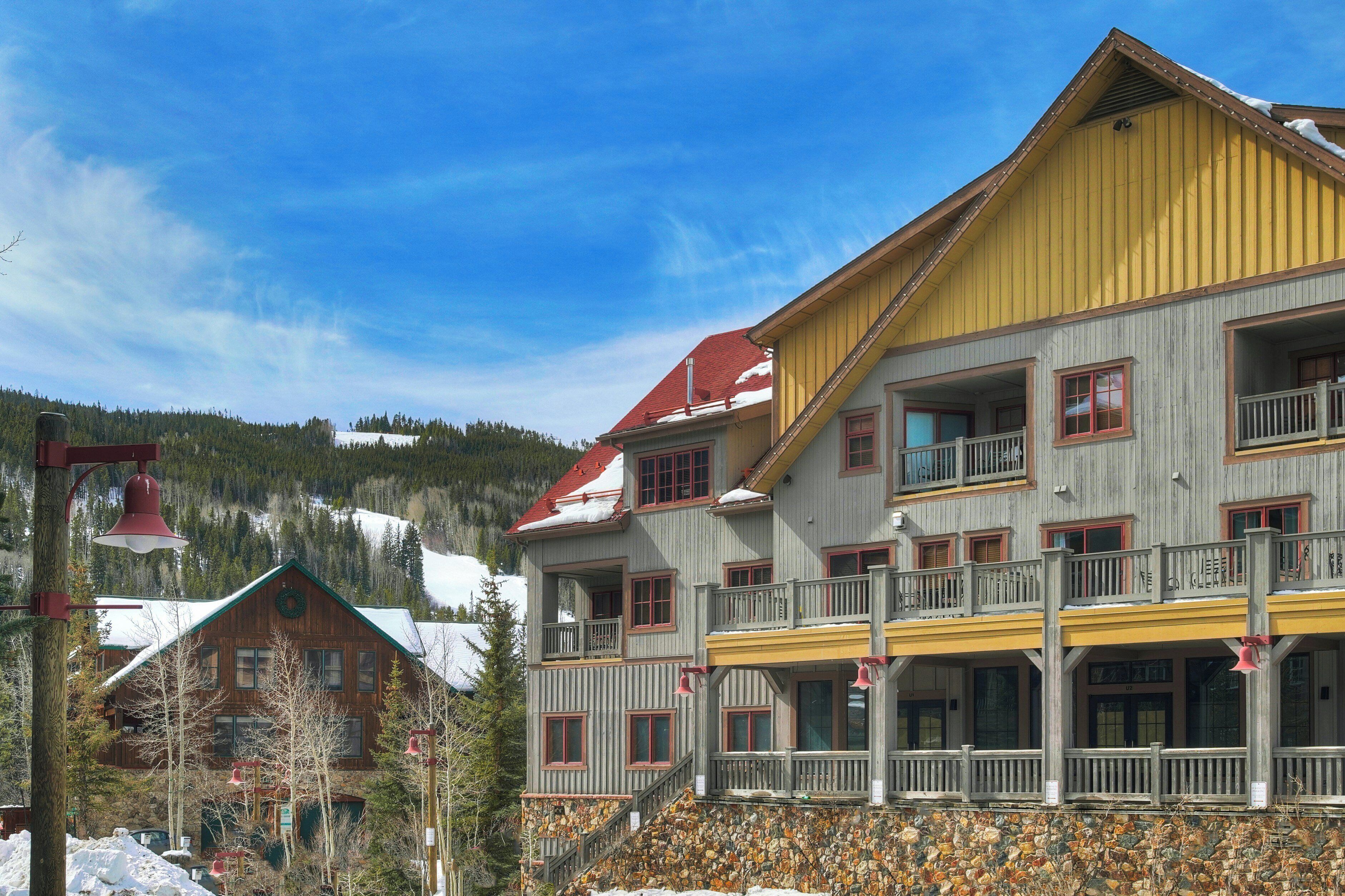 A multi-story building with balconies, a red roof, and a stone foundation.