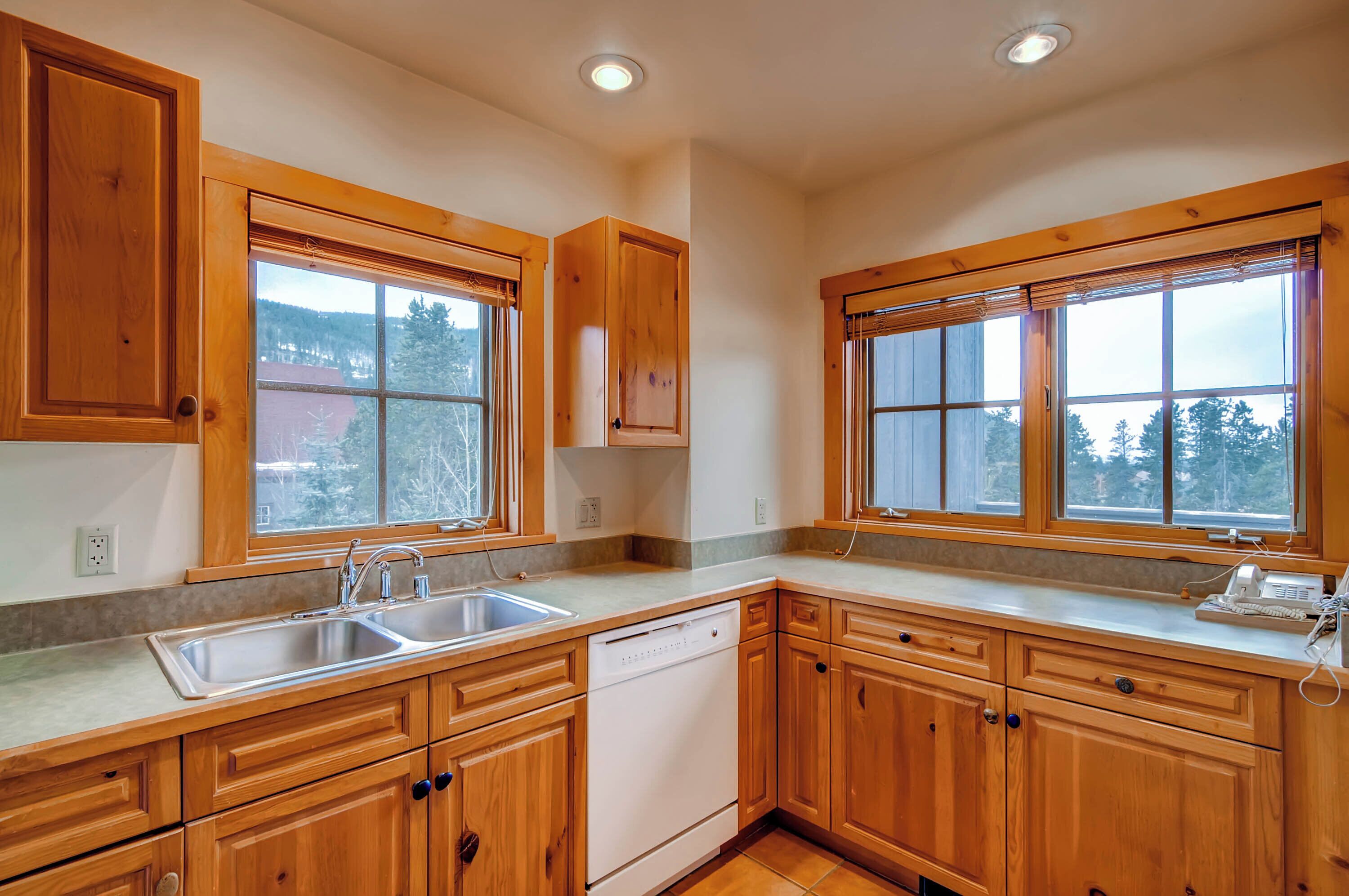 A kitchen with wooden cabinets, a dishwasher, and a double sink.