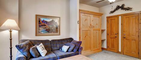 A living room with a blue plaid sofa, a table, a lamp, and wooden cabinets.
