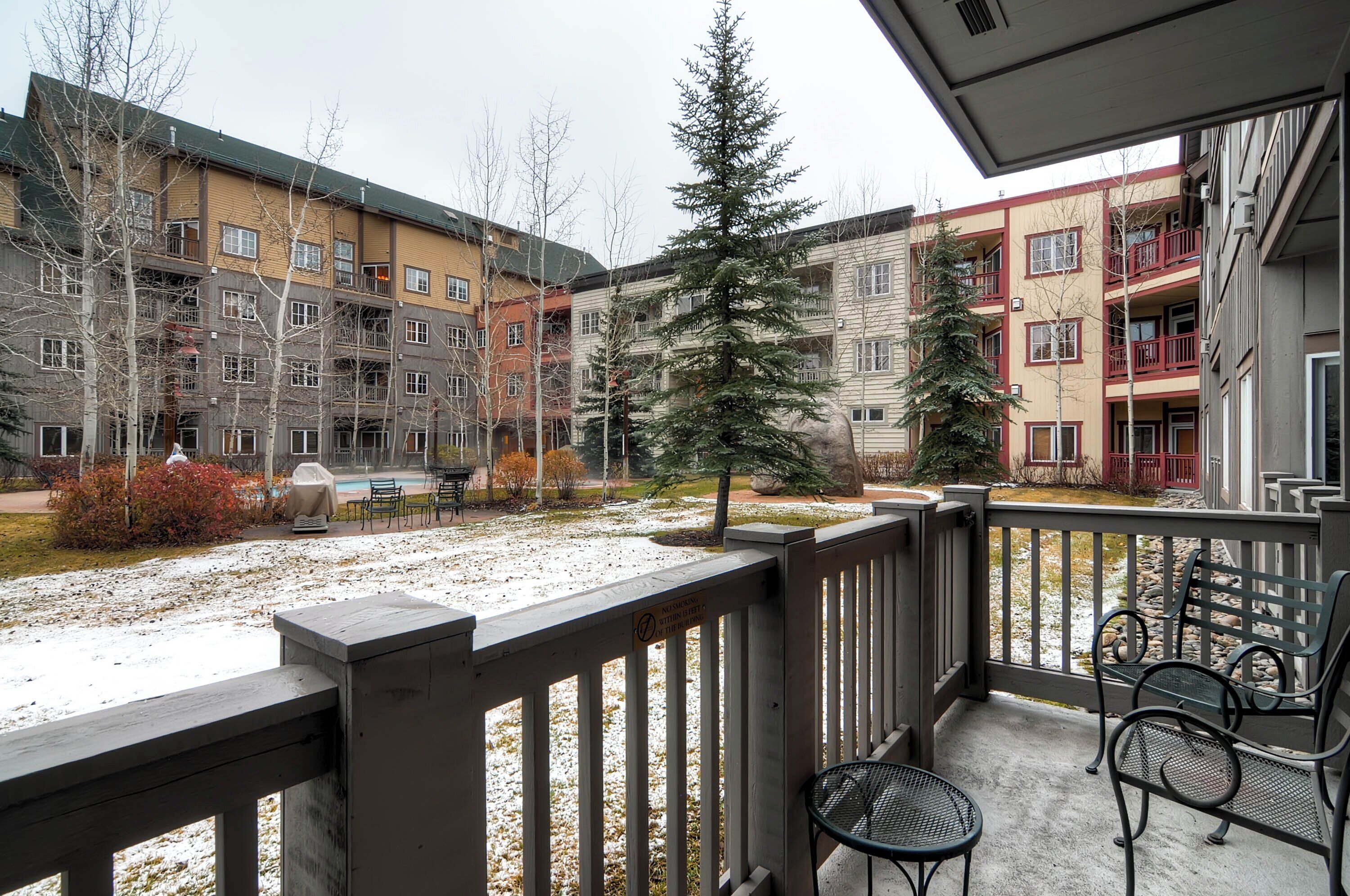 A courtyard with a covered seating area, a snow-covered ground, and multi-story buildings with balconies.
