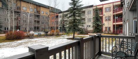 A courtyard with a covered seating area, a snow-covered ground, and multi-story buildings with balconies.