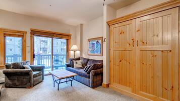 A living room with a sofa, a coffee table, and a large wooden wardrobe.
