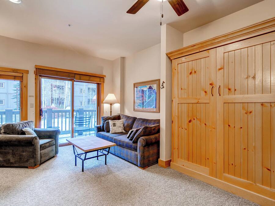 A living room with a sofa, a coffee table, and a large wooden wardrobe.