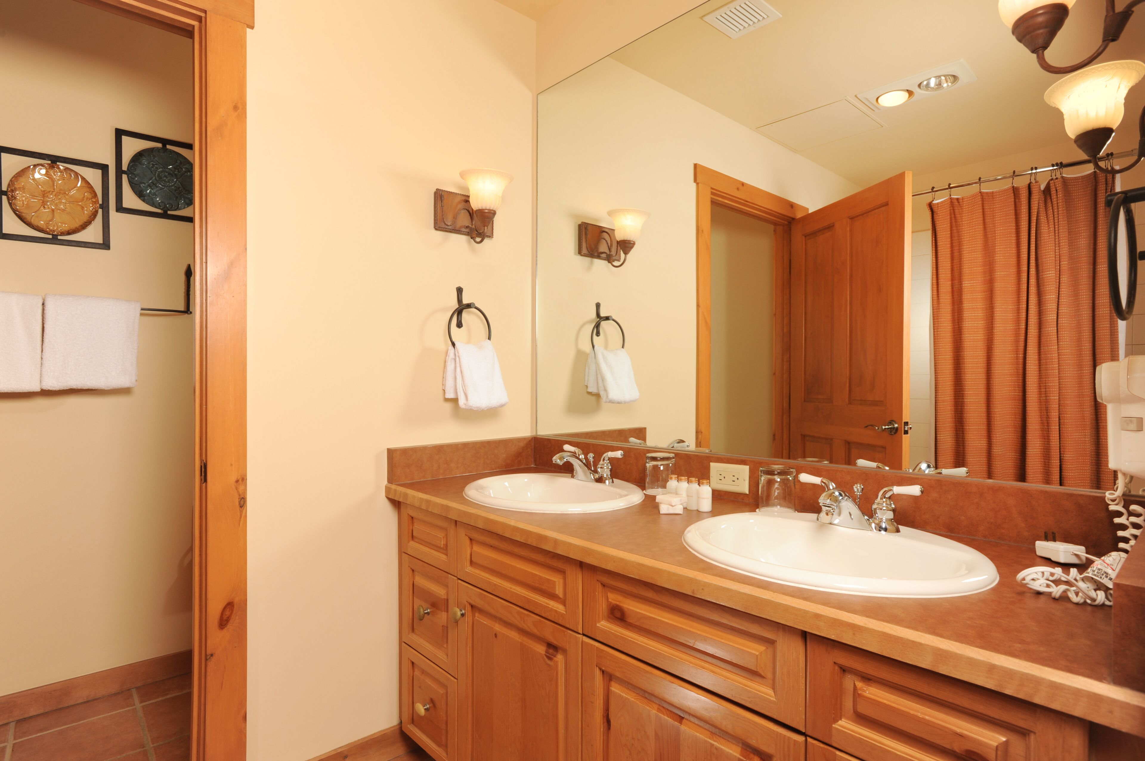 A bathroom with two sinks, wooden cabinetry, and a large mirror.