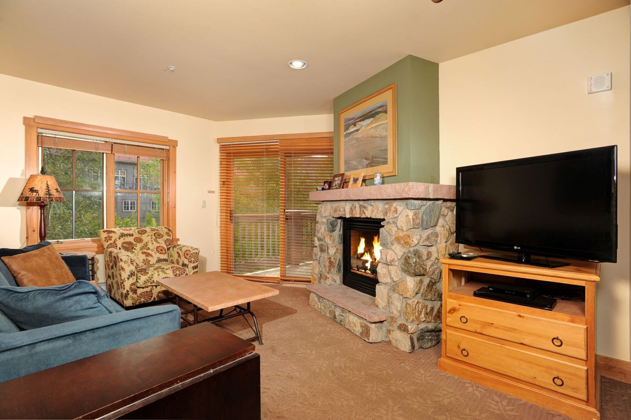 A living room with a stone fireplace, a television on a wooden stand, a sofa, and a coffee table.