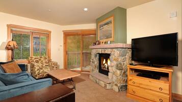 A living room with a stone fireplace, a television on a wooden stand, a sofa, and a coffee table.