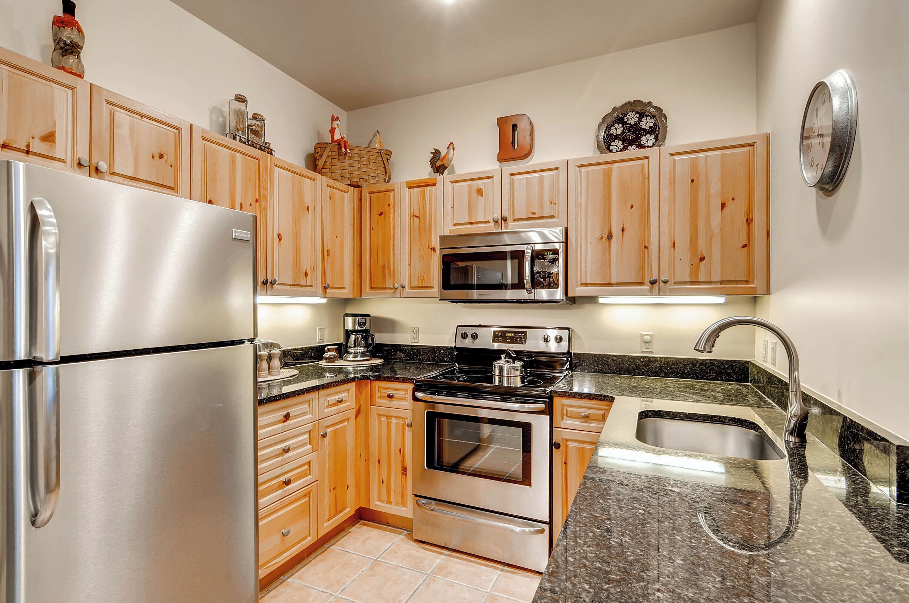 A kitchen with wooden cabinets, stainless steel appliances, a granite countertop, and a stainless steel sink.