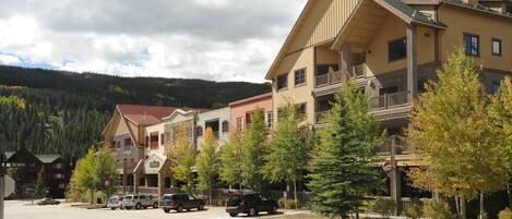 A multi-story hotel with balconies, a parking lot, and a mountainous backdrop.