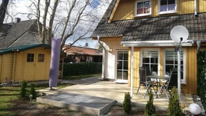 A two-story house with a patio area, satellite dish, and a small garden. - Charmantes 60m² Ferienhaus, Ausgestattet mit Terrasse (Zinnowitz)