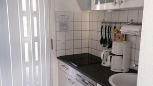 A kitchen with white cabinets, a black countertop, a coffee maker, and a sink. - Charmantes 60m² Ferienhaus, Ausgestattet mit Terrasse (Zinnowitz)