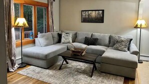 Ein Wohnzimmer mit einem grauen Ecksofa, einem Couchtisch und zwei Stehlampen.
